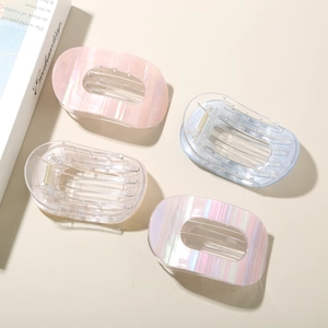 Détail de quatre grandes pinces à cheveux ovales avec fini nacré irisant et design évidé
