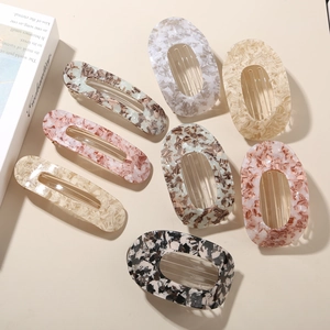 Close-up of seven flat oval and rectangular acetate hair clips with marble patterns