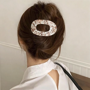Close-up of a large oval amber marble hair clip worn on an elegant hairstyle
