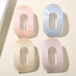 Détail de quatre barrettes à cheveux ovales nacrées aux motifs géométriques creux