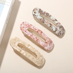 Détail de trois barrettes en acétate effet marbre avec des pinces métalliques dorées