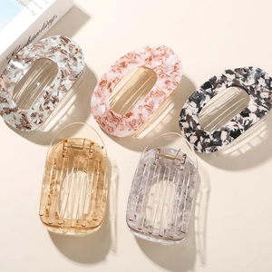 Flat round acetate hair clips in marble and amber colors shown on white background