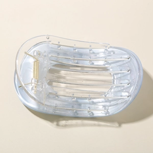 Vue détaillée de la pince à cheveux en acrylique transparent avec ressort en métal doré