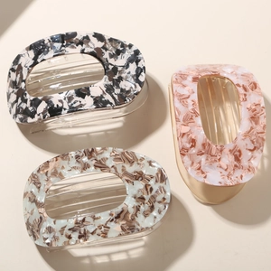 Close-up of three acetate duckbill hair clips in marble and amber textures