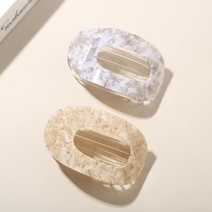 Detailed macro view of two marbled acetate hair clips in white and caramel beige tones