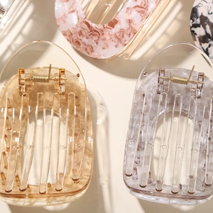 Close-up of premium acetate hair claws with marble and amber patterns and metal springs
