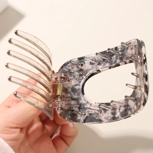 Detail view of large marble and transparent hair clip with golden metal spring