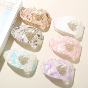 Detail of hollow heart-shaped acetate hair claws featuring marble texture in six colors
