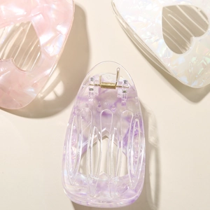 Macro detail of heart-shaped acetate hair clip with pearlescent marble texture