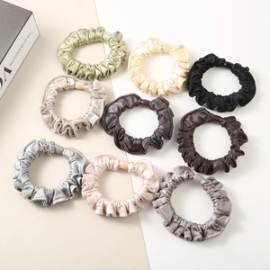 Flat lay of nine premium satin silk scrunchies in diverse earth tones for hair styling