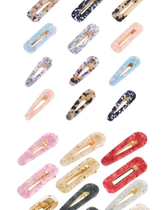Détail des barrettes en acétate effet marbre avec fermoir en métal doré de divers motifs