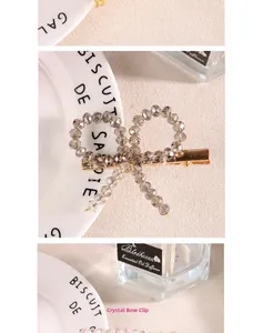 Détail d'une pince à cheveux nœud en perles de cristal gris avec base en métal doré