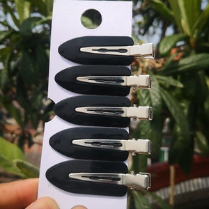 Detail showing set of five black leaf-shaped hair clips on a white display card pack