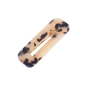 Detailed macro view of an acetate hair clip with brown tortoiseshell pattern and gold metal spring