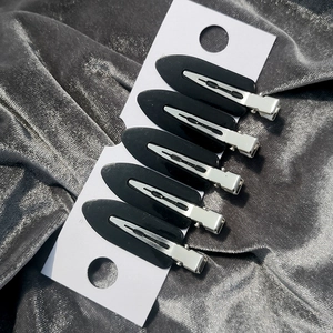 Close-up of 5-piece set of black crease-free hair clips on white card and grey velvet