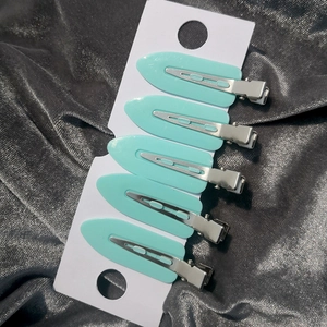 Detail of five mint green leaf hair clips organized on a white card display