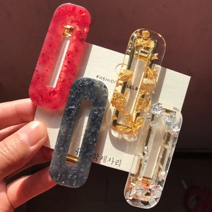 Handheld set of four geometric acetate hair clips with gold flakes and amber effect