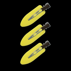 Macro detail of three yellow creaseless hair clips with silver metal springs on black background