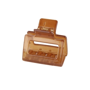 Detail view of small amber rectangular hair claw clip with golden metal spring