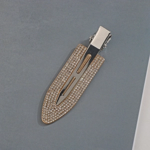 Dettaglio macro della molletta per capelli dorata con strass di cristallo e base in metallo