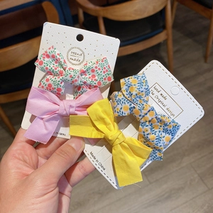 Detail view of handmade fabric bow hair clips in floral and solid colors on cards