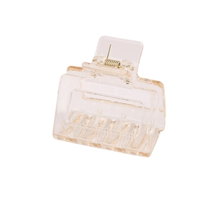 Detail view of champagne rectangle acrylic hair claw clip with golden metal spring