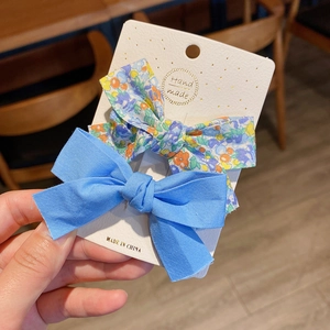 Detail of floral and blue fabric bow hair clips on handmade card display packaging