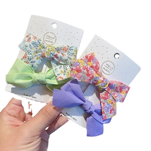Set of four floral and solid color cotton bow hair clips on handmade display card