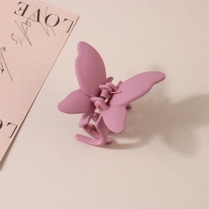 Gros plan sur la pince à cheveux papillon rose mat avec mécanisme à ressort métallique