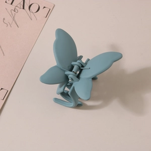 Détail de la pince à cheveux papillon minimaliste avec une finition bleue Morandi mate