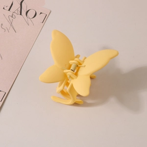 Détail de la pince à cheveux papillon jaune mat avec un mécanisme de ressort en métal