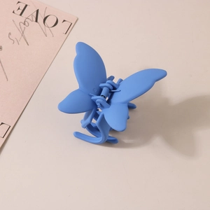 Gros plan détaillé d'une pince à cheveux papillon bleue au fini mat avec ressort métal