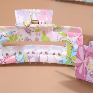 Pinza per capelli rettangolare con stampa di farfalle colorate su sfondo chiaro