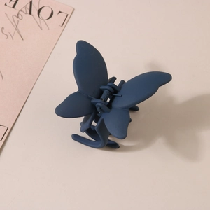 Détail de la pince à cheveux papillon bleu marine mat avec ressort métallique et texture