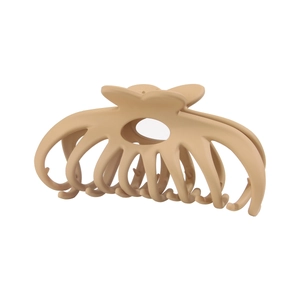 Detail view of large matte beige hair claw clip with cross teeth and heart shaped handle