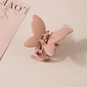 Détail d'une pince à cheveux papillon rose mat montrant le ressort et la texture