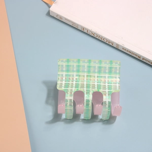 Detail view of a green and white plaid hair claw clip with a light pink lining finish
