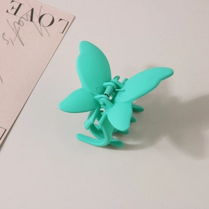Détail d'une pince à cheveux papillon vert menthe mat avec ressort en métal argenté