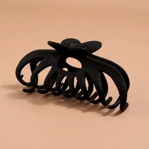 Close-up of a large black matte hair claw clip with multi-tooth structure and metal spring