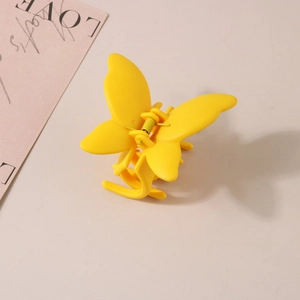 Vue détaillée d'une pince à cheveux papillon jaune mat avec un ressort métallique robuste