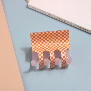 Detail of large orange and white checkered hair claw clip with glossy resin finish