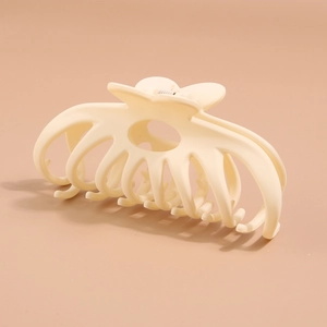 Detail view of cream-colored large hair claw clip with heart-shaped handle design