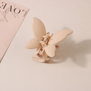 Détail de la pince à cheveux papillon avec finition beige mat et mécanisme à ressort robuste
