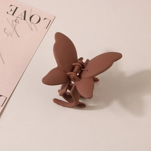Détail d'une pince à cheveux papillon marron mat avec une texture givrée haut de gamme