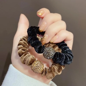 Dettaglio di elastici per capelli in velluto nero e oro con sfera di strass scintillanti