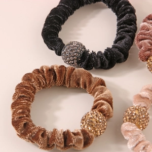 Dettaglio di elastici in velluto con sfere di cristallo in nero, marrone e beige