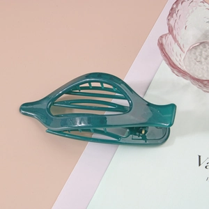 Détail macro d'une pince à cheveux vert foncé brillante au design profilé denté