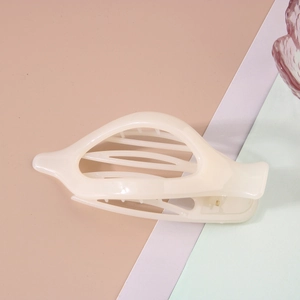 Vue latérale macro d'une pince à cheveux crème au design épuré et structure ajourée