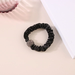 Dettaglio dell'elastico per capelli in velluto nero con una sfera di strass scintillanti e luce