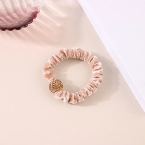 Dettaglio dell'elastico in velluto beige con ciondolo a sfera in strass dorati